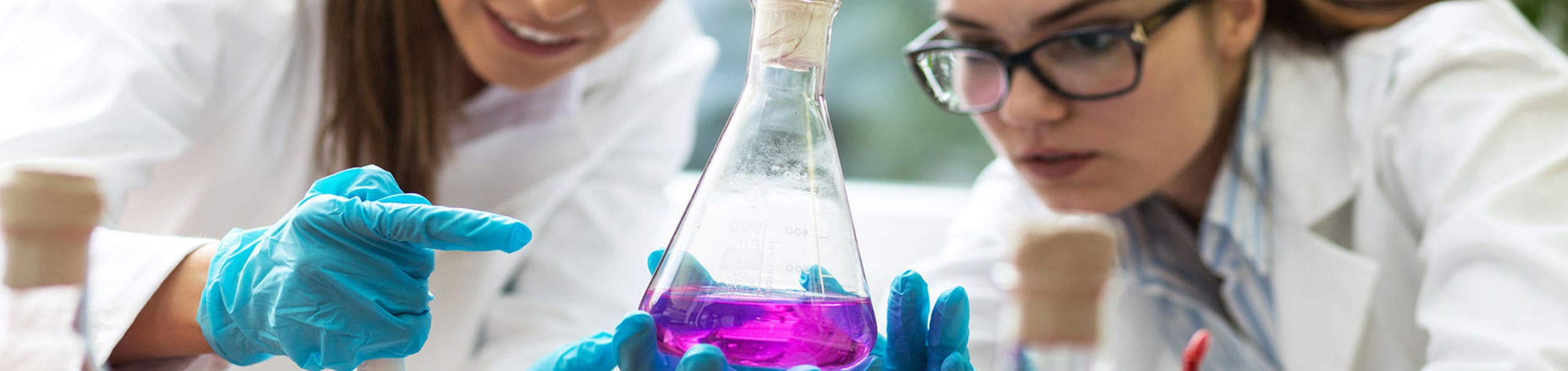 lab students looking at beaker with purple liquid (c) iStock